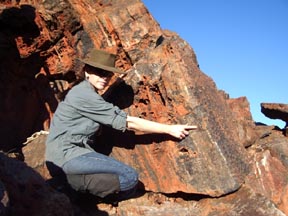 La imagen muestra a Abigail Allwood de la Universidad Macquarie señalando el arrecife fósil que descubrió en Pilbara